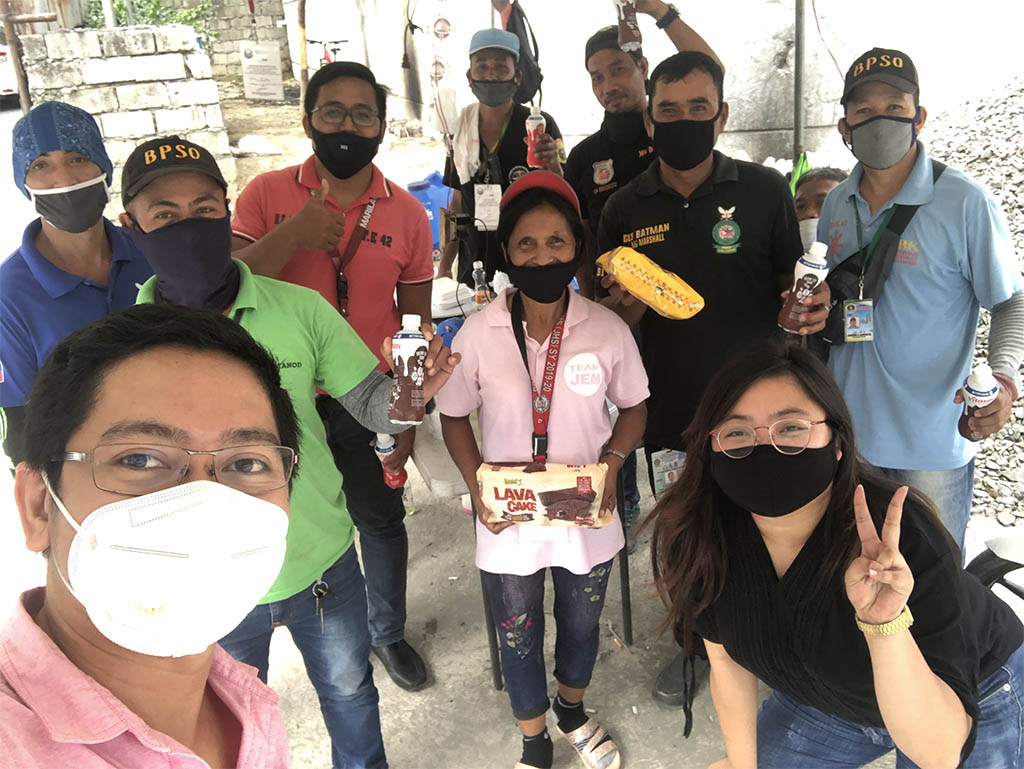 A group of people wearing face masks seem to be smiling while taking pictures.