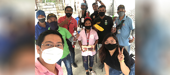 A group of people wearing face masks seem to be smiling while taking pictures.